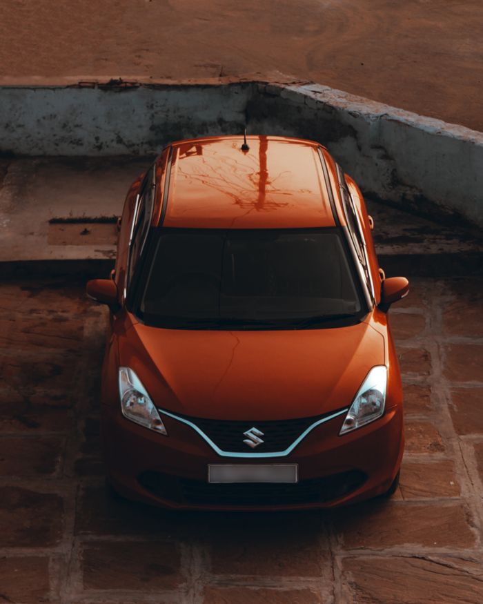journey Aerial view of a red Suzuki car parked outdoors on a tiled surface, showcasing vehicle design.
