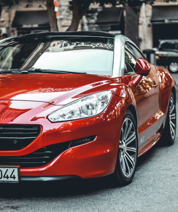 who-we-are Vibrant red sports car parked in Baku, Azerbaijan, showcasing sleek design and modern style.