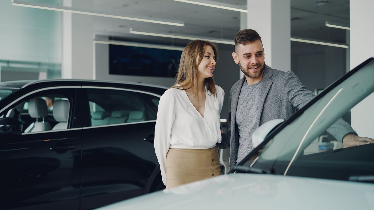 services-01 Smiling couple exploring cars at dealership, enjoying shopping experience.