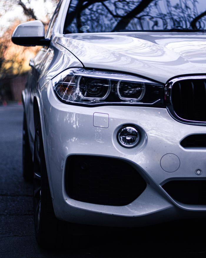 Close-up of a luxury car headlight with a sleek design, captured at twilight.