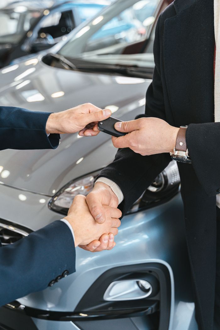 services-04 Close-up of a business handshake as car keys are handed over, symbolizing a new car purchase.
